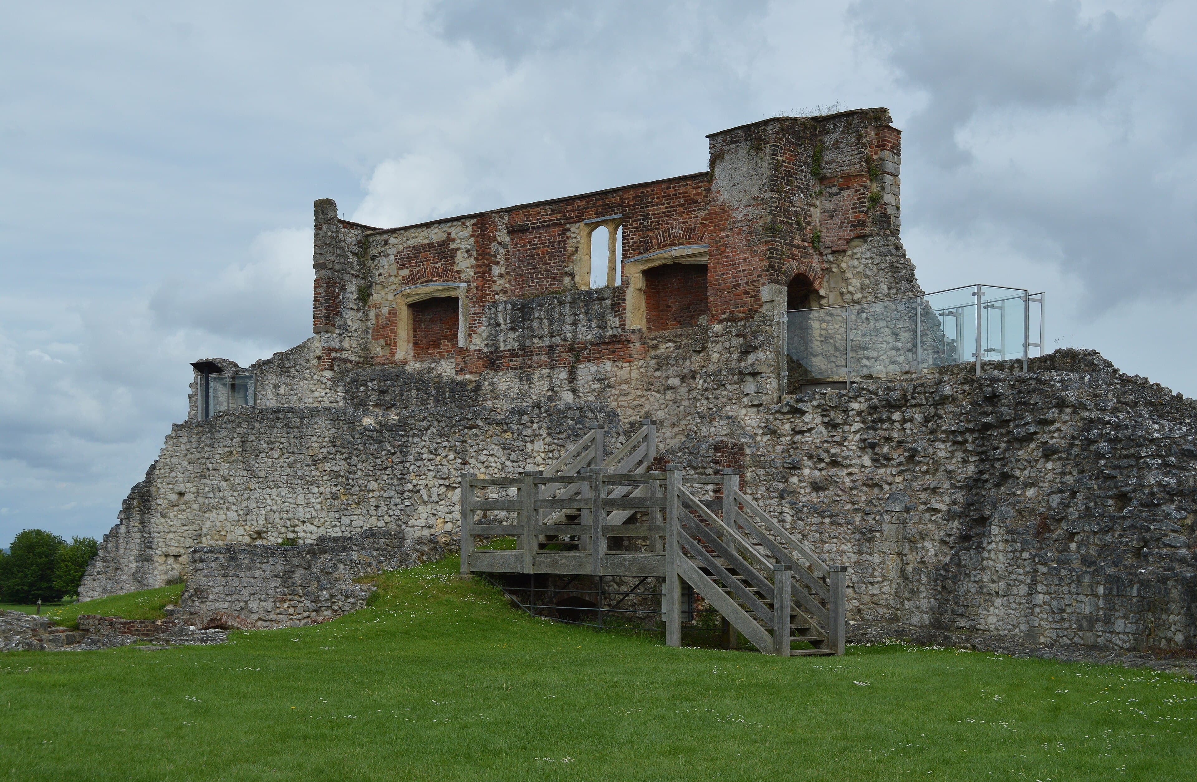 Ruined flint and red brick walls of Farnham Castle keep with wooden steps and glass viewing platform